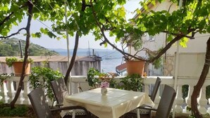 Un espace extérieur aménagé avec une table et des chaises, entouré de plantes en pot et offrant une vue sur une étendue d’eau.