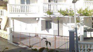 Un immeuble blanc à plusieurs étages, doté de balcons, d’un parking sécurisé et donnant sur la rue.