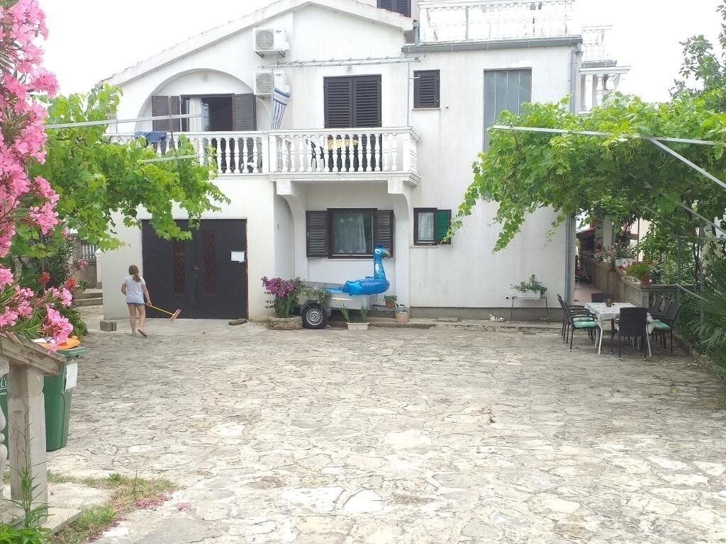 Une cour avec un bâtiment blanc, une chaise bleue et une table entourée de chaises.