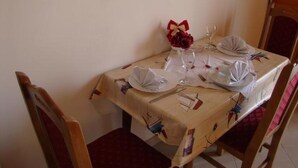 Une table à manger dressée avec de l’assiette blanche, des serviettes pliées et un verre de vin rouge.