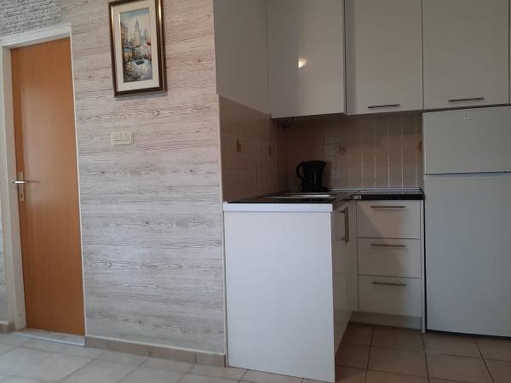 A compact kitchen with white cabinets, a small countertop, and a coffee maker.