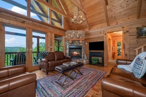 Un interior de cabaña acogedor, con chimenea de piedra, muebles de cuero y un amplio ventanal con vistas a un paisaje pintoresco.