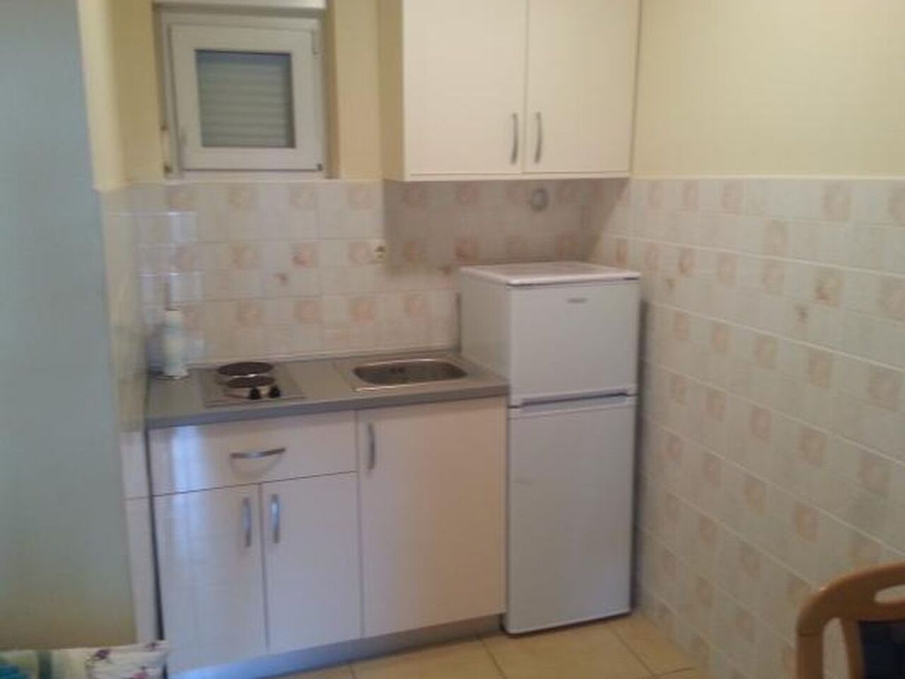 A compact kitchen with white cabinets, a sink, a stove, and a refrigerator.