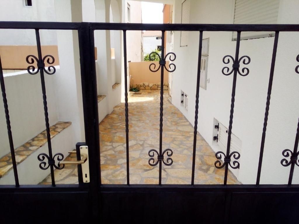 A gated entrance with a stone-tiled pathway leading to a building.