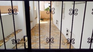 Une entrée fermée par un portail, avec un chemin dallé de pierres menant à un bâtiment.