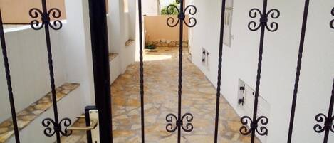 A gated entrance with a stone-tiled pathway leading to a building.