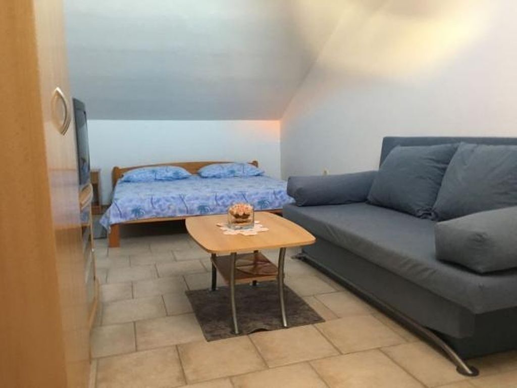 A small, compact room with a bed, a sofa, and a small table.