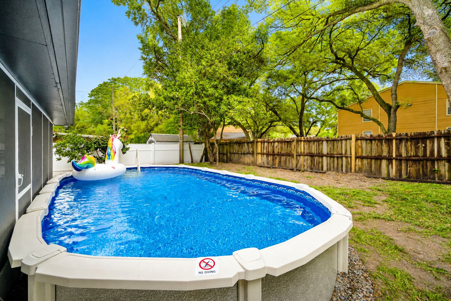 Un patio trasero con piscina, flotador inflable y cerca de madera.