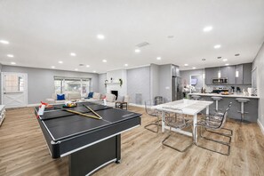 A modern living space with a ping pong table, a dining area, and a kitchen. - Heated Pool, 5BR Sleeps 14, Game Table | 15 Min to Busch Gardens, Tampa (Tampa)