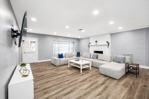 A modern living room with a sectional sofa, a coffee table, and a fireplace.