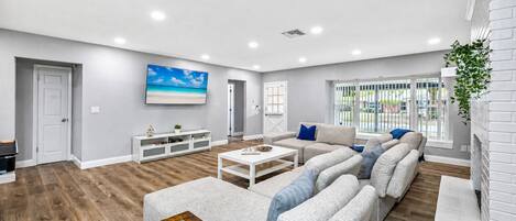 Un salón amplio con un sofá modular grande, una mesa de centro y un televisor de pantalla plana montado en la pared.