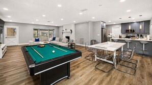 Un salon moderne comprenant une table de billard, un coin repas et une cuisine.