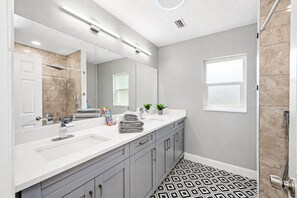 A modern bathroom with a large mirror, dual sinks, and a patterned floor. - Spacious, Modern and Fully Updated Gorgeous Home (Tampa)
