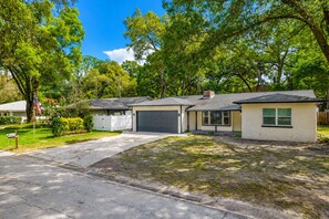 Una casa residenziale con garage, vialetto e giardino antistante alberato con cassetta postale.