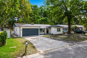 A residential property with a garage, a small attached structure, and a driveway leading to a parked car. - Heated Pool, 5BR Sleeps 14, Game Table | 15 Min to Busch Gardens, Tampa (Tampa)