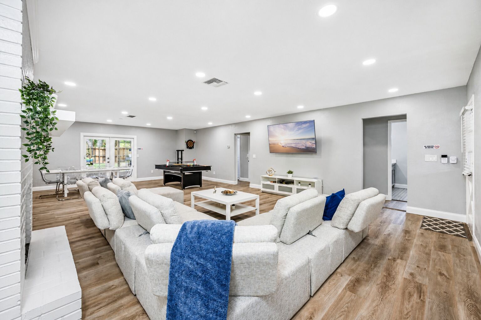 A spacious living room with a pool table, a sofa set, and a television.