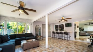 A spacious living area with a sectional sofa, ottoman, and a dining area with bar stools.