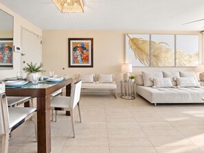 Een moderne woonkamer met een eethoek, een zithoek en een schilderij aan de muur.