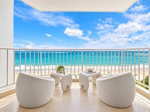 A balcony with a view of the ocean, white chairs, and a small table with a plant. - Beachfront Walk 2 Eat Million View Location (Carolina)