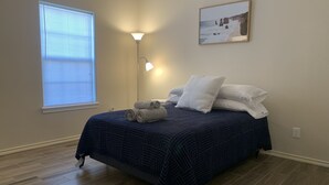 A bedroom with a bed, a window with blinds, a floor lamp, and a painting on the wall. - King Bed Cozy Pet Friendly Condo with Private Terrace in a Calm Gated Community (Edinburg)
