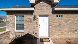 A two-story brick house with a white front door, a small window, and a mailbox. - King Bed Cozy Pet Friendly Condo with Private Terrace in a Calm Gated Community (Edinburg)