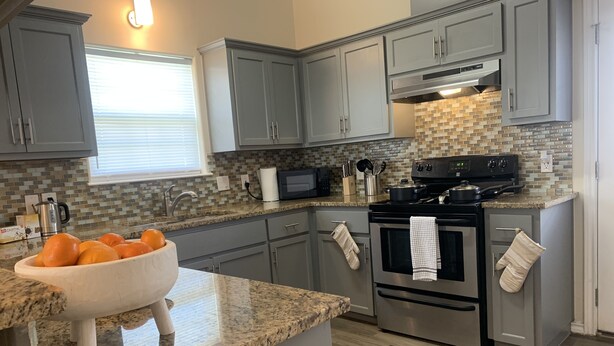 A modern kitchen with grey cabinets, a granite countertop, a stainless steel stove, and a microwave. - King Bed Cozy Pet Friendly Condo with Private Terrace in a Calm Gated Community (Edinburg)