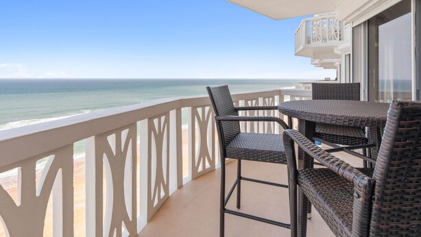 Een balkon met rieten meubilair en uitzicht op de oceaan.