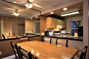 Enjoy meals in this dining area with a table and chairs, kitchenette, and ceiling fan for ventilation.