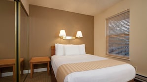 A hotel room with a bed, bedside tables, a mirror, and a window with blinds. - *7 night stay at Steamboat Springs, CO* (Steamboat Springs)