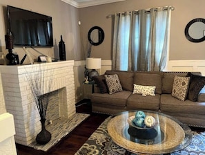 Cozy living room with a fireplace, comfortable sofa, and flat-screen TV.