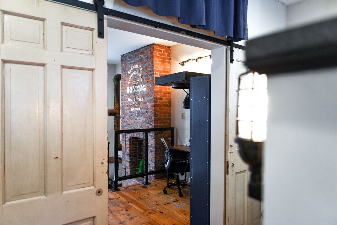 Una habitación con chimenea de ladrillo, un escritorio y una silla.