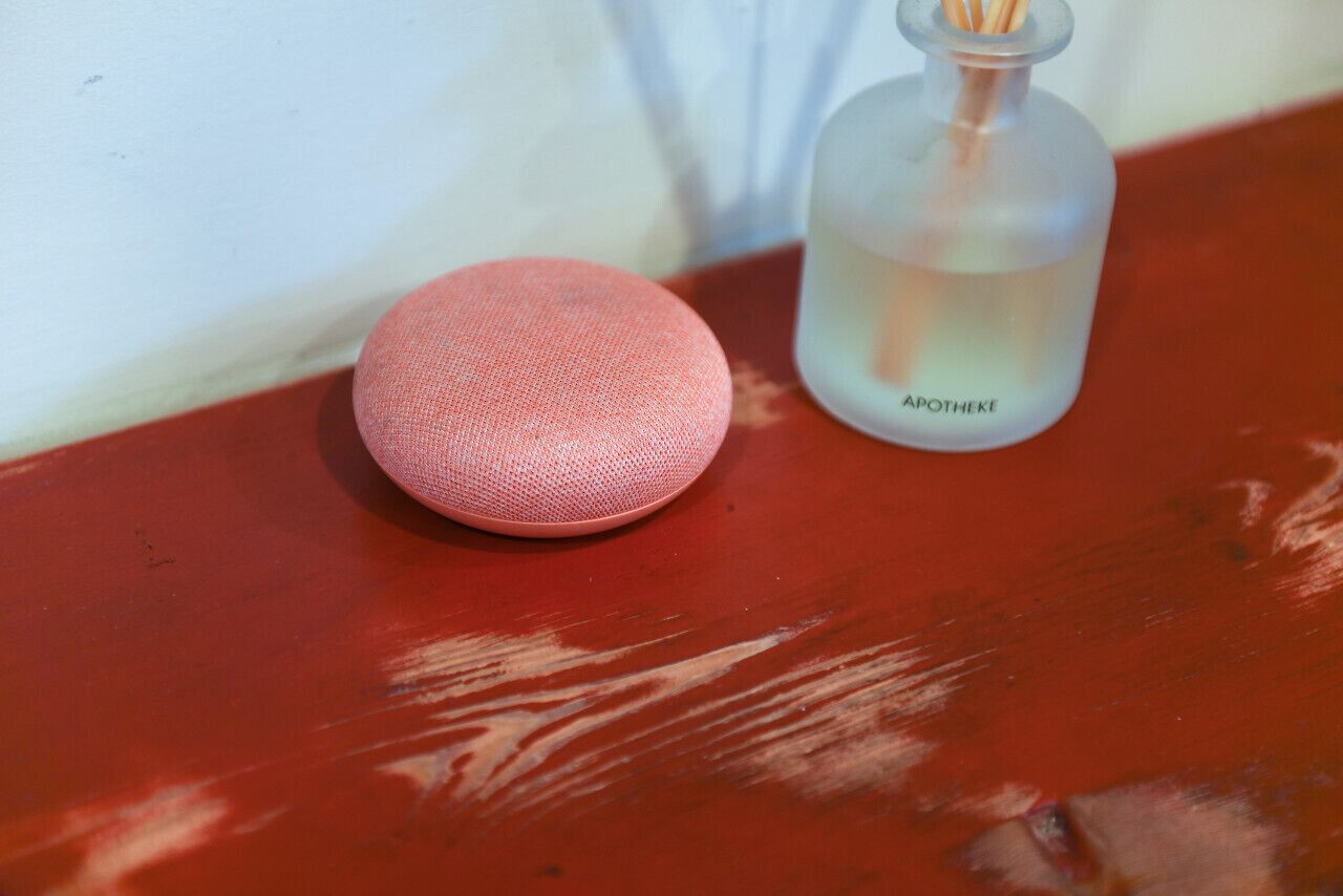 Une surface rouge avec un petit objet rose et une bouteille transparente portant l’étiquette « APOTHEKE ».