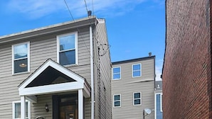 A two-story residential building with a front porch and a small staircase leading to the entrance. - 1210 James St. #2 · Free Off Street Parking! (Pittsburgh)