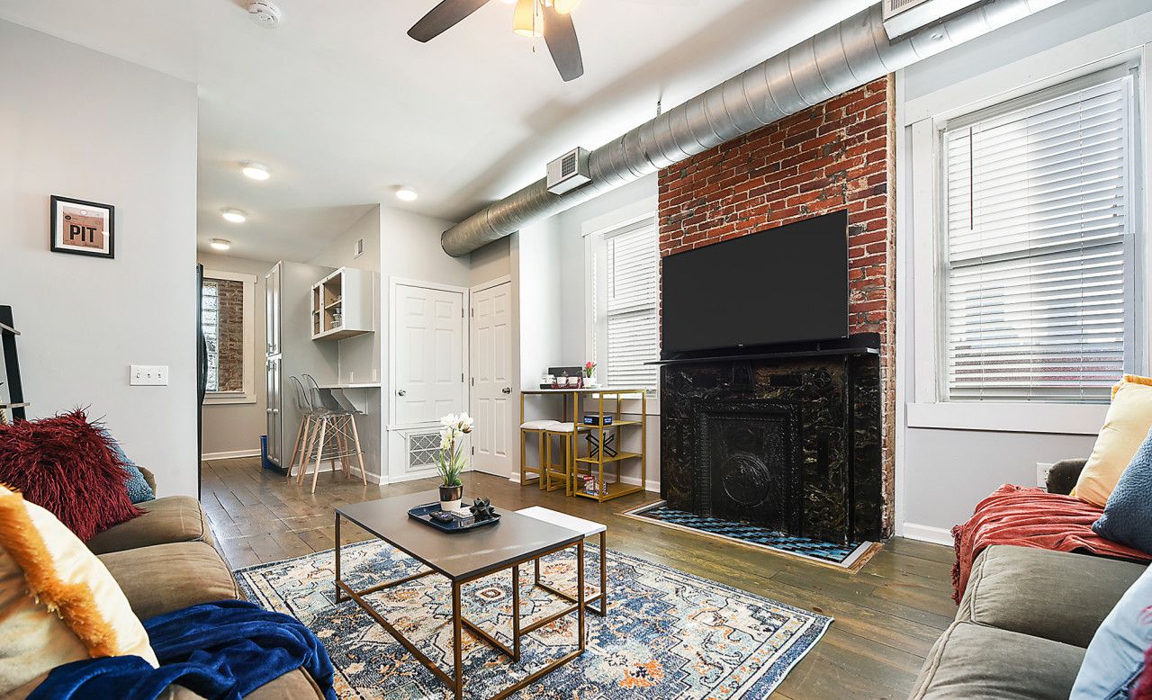 A modern living room with a fireplace, a flat-screen TV, and a cozy seating area.