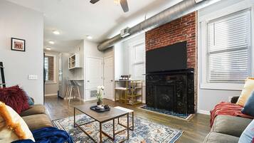 A modern living room with a fireplace, a flat-screen TV, and a cozy seating area.