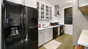 Una cocina moderna con armarios blancos, un refrigerador negro, una cafetera y una estufa.