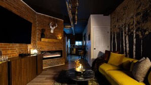 Un salon chaleureux avec une cheminée en briques, un canapé jaune et un téléviseur fixé au mur.