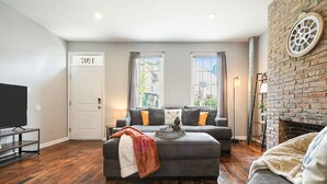 A living room with a grey sofa, a television, and a fireplace. - 1207 Ocala - Boat House - North Side (Pittsburgh)