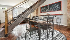 A dining area with a wooden staircase, a black and white patterned rug, and a large decorative wall piece. - 1207 Ocala - Boat House - North Side (Pittsburgh)