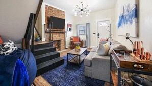 A modern living room with a fireplace, a staircase, a sofa, and a coffee table. - 190.5 44th St. - Lawrenceville (Pittsburgh)