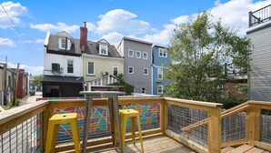 A wooden deck with a colorful mosaic wall, two yellow stools, and a metal railing. - 190.5 44th St. - Lawrenceville (Pittsburgh)
