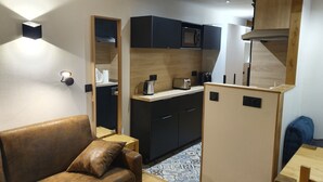 A compact kitchenette with a microwave, toaster, and kettle, a brown leather sofa, and a small dining table with chairs. - Studio Cabin 25m² at the foot of the slopes (Val Thorens)
