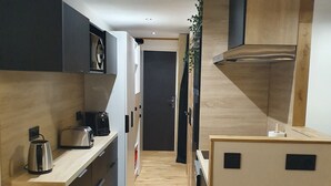 A compact kitchen with modern appliances, a patterned tile floor, and a small wooden table. - Studio Cabin 25m² at the foot of the slopes (Val Thorens)