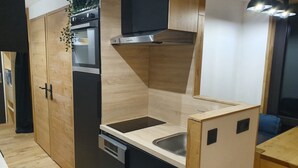 A compact kitchen with wooden cabinets, a built-in oven, a microwave, and a sink. - Studio Cabin 25m² at the foot of the slopes (Val Thorens)