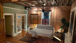 A cozy bedroom with a bed, a chair, a ceiling fan, and a window.