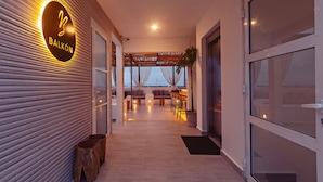 Un interior moderno con piso de madera, una zona de estar con mesa y sillas, y vista al mar a través de amplios ventanales.