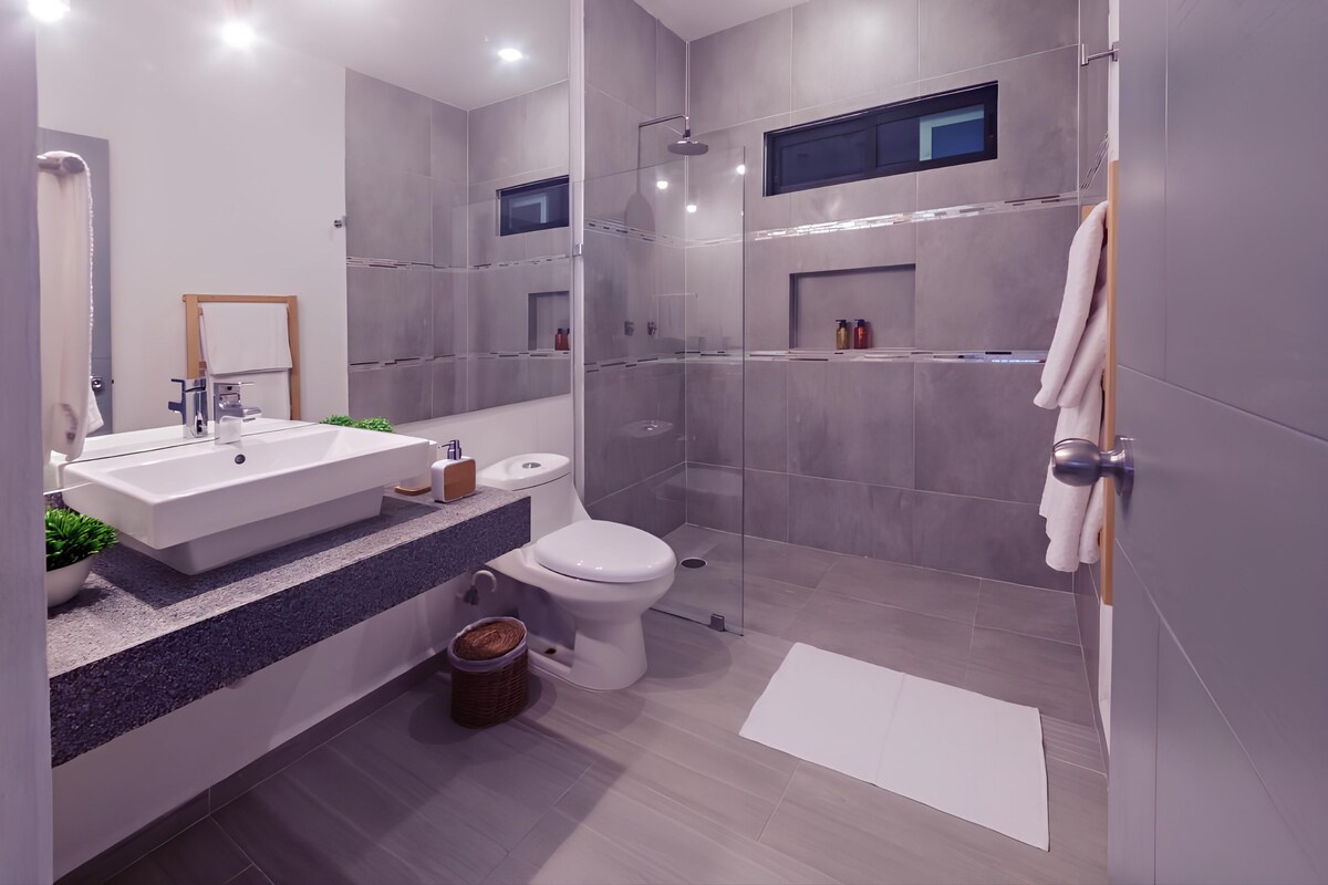 Un baño moderno con un lavamanos grande, inodoro y zona de ducha.