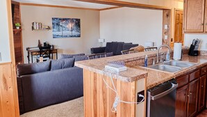 A compact living space with a kitchenette, a sofa, a dining table, and a painting on the wall. - Cozy Condo at Summit- 103D (Snowshoe)