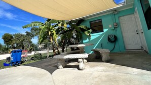 Un espace patio doté d’un auvent, de sièges d’extérieur et d’une porte donnant accès à un bâtiment.