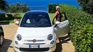 A white car parked on a stone driveway with a clear blue sky and ocean view in the background. - Top location - tranquillity - pool - garden & sea view (Zambrone)